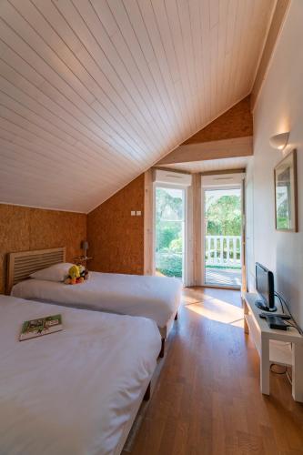 - une chambre avec 2 lits, une télévision et une fenêtre dans l'établissement Lagrange Vacances - Eden Club, à Lacanau-Océan