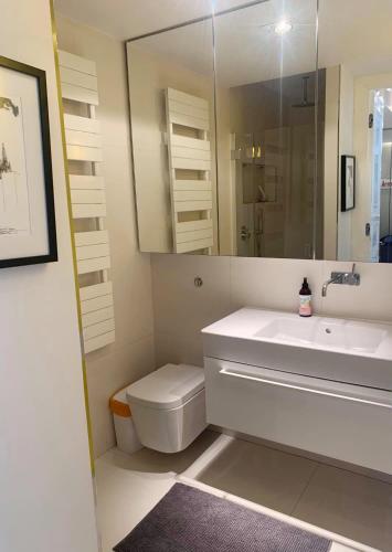 a bathroom with a sink and a toilet and a mirror at Apartament z balkonem in Sopot