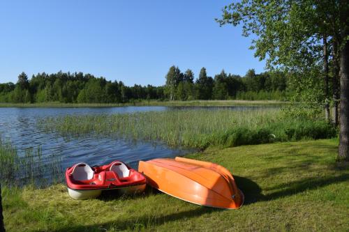 two boats sitting on the grass next to a lake at Mežmāja Spārītes in Geraņimova