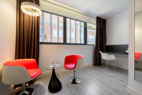 una sala de espera con sillas rojas y una mesa en Eurostars Central, en Madrid
