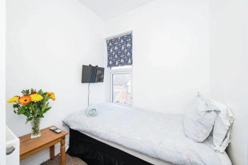 a bedroom with a bed and a vase of flowers on a table at 4 Bedroom House For Corporate Stays in Kettering in Kettering