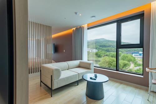 a living room with a couch and a large window at Hound Hotel Hyeoksindosi Branch in Daegu