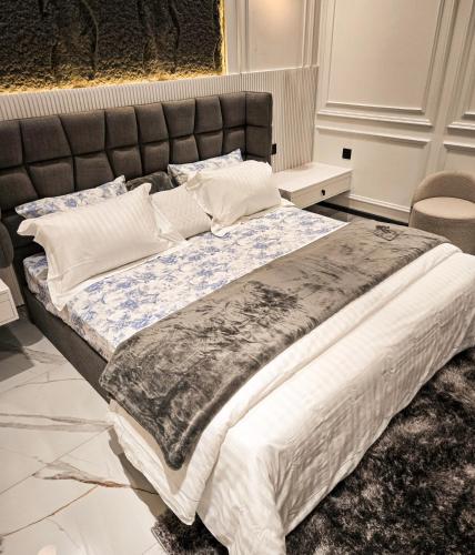 a bedroom with a large bed with a black headboard at The White Suites in Karachi