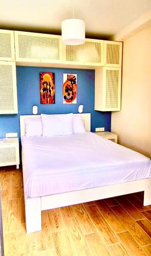 a bedroom with a white bed with a blue wall at Terrace Kaprovan in Shekvetili
