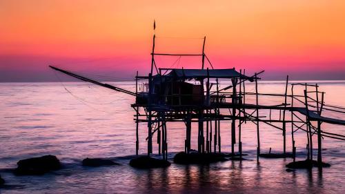 a pier on the ocean with a sunset in the background at Il Dolce Risveglio in Fossacesia