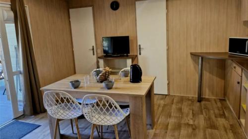 une cuisine avec une table en bois et deux chaises dans l'établissement Kokua Vacances présente MOBIL HOME résidentiel toutes options camping 3 étoiles LESCAR, à Lescar