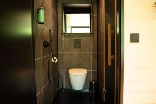a bathroom with a toilet and a window and a door at Chic Sauna Cabin Near the Sea - MULIN Cabin Nº05 in Tsitre