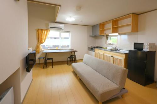 a living room with a couch and a kitchen at Hill House B NakaFurano Hokkaido JAPAN in Nakafurano