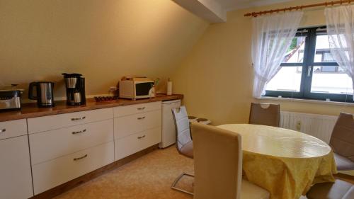 a kitchen with a table and a microwave and a window at Haus Heidi, Wellness und Ayurveda in Kurort Rathen