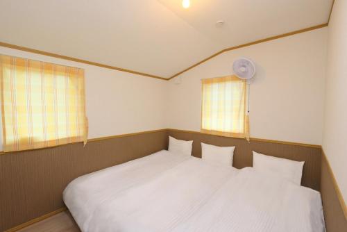 - une chambre avec un lit blanc et 2 fenêtres dans l'établissement Hill House B NakaFurano Hokkaido JAPAN, à Nakafurano