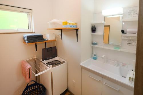 La petite salle de bains est pourvue d'un lavabo et d'un lave-linge. dans l'établissement Hill House B NakaFurano Hokkaido JAPAN, à Nakafurano