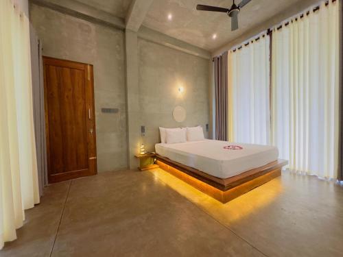 Un dormitorio con una cama blanca y una ventana grande. en Tarragon Leisure, en Matara