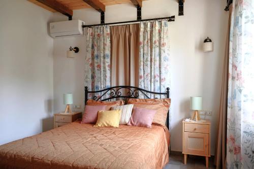 a bedroom with a bed with pink and yellow pillows at LIORIZA Country Houses in Kalamaki
