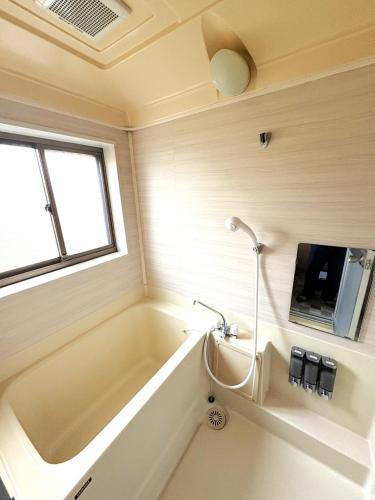 a bathroom with a tub and a tv on the wall at Nagomi Hanare in Matsumoto