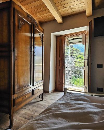 a bedroom with a wooden cabinet and a large window at La Casa nel Nebbiolo in Pont-Saint-Martin