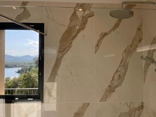 a bathroom with a marble shower with a window at CADIAMARE in Zonza