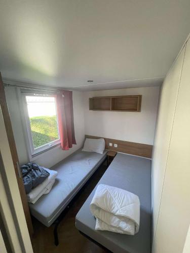 une petite chambre avec deux lits et une fenêtre dans l'établissement Mobilhome Camping Les Charmettes - Fun pass non inclus, aux Mathes