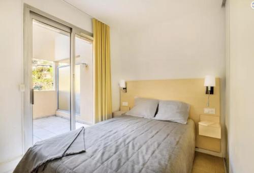 une chambre avec un lit et une porte coulissante en verre dans l'établissement Appartement calme, climatisé, 15 min de la plage, Cannes la Bocca, à Cannes