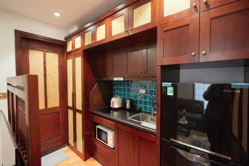 a kitchen with wooden cabinets with a sink and a microwave at Camellia Residence Hanoi in Hanoi