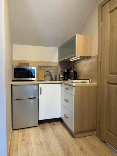 a small kitchen with white cabinets and a microwave at APARTAMENTY LAVENDERIA z widokiem na Górę Parkową, blisko centrum in Kudowa-Zdrój