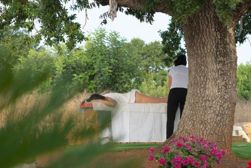 a man laying on a bed under a tree at Trulli Vulés in Ostuni