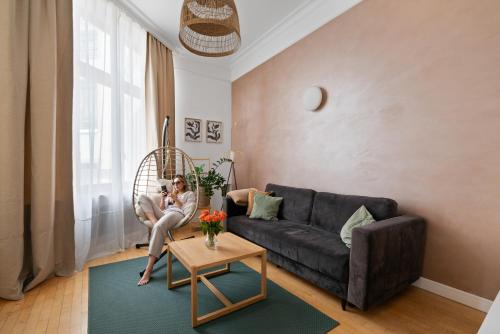 a woman sitting on a couch in a living room at Golden Market Square - 3Rooms, 90m2 of Comfort & Quiet - AS HOME Apartamenty R502 in Wrocław