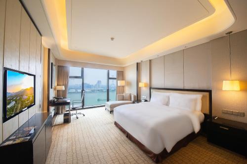 a hotel room with a large bed and a television at Junluxe Hotel Guangzhou Zengcheng-Free Shuttle Bus For Canton Fair in Zengcheng