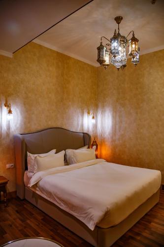 a bedroom with a large bed with a chandelier at Jannat Regency Jalal-Abad in Jalal-Abad