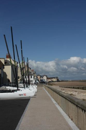 une rangée de bateaux garés sur un trottoir à côté d'une plage dans l'établissement La Grandcopaise Chambres et Studios, à Grandcamp-Maisy