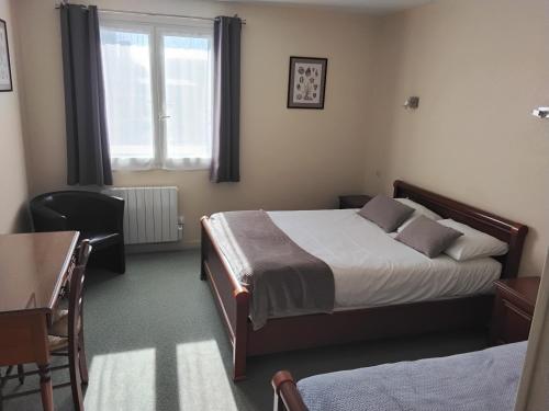 une chambre avec un lit, un bureau et une fenêtre dans l'établissement La Grandcopaise Chambres et Studios, à Grandcamp-Maisy