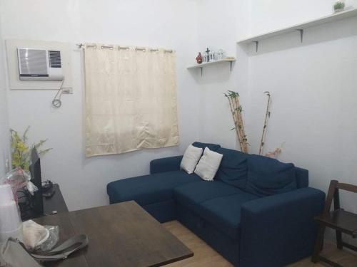 ein Wohnzimmer mit einem blauen Sofa und einem Tisch in der Unterkunft Apple One Banawa Heights in Cebu City