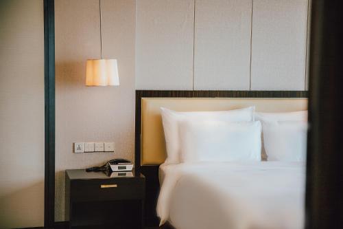 a bedroom with a bed and a phone on a night stand at Junluxe Hotel Guangzhou Zengcheng-Free Shuttle Bus For Canton Fair in Zengcheng