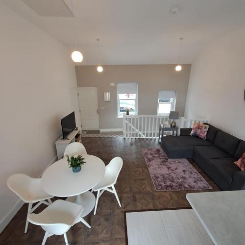 a living room with a couch and a table and chairs at 1A Cathedral Place - Cathedral Townhouses Cobh in Cobh