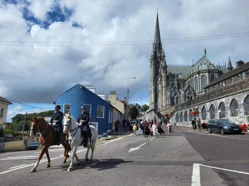 two police officers riding horses down a city street at 1A Cathedral Place - Cathedral Townhouses Cobh in Cobh