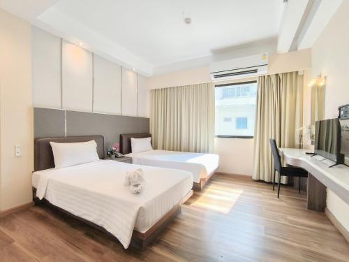 a hotel room with two beds and a desk at Citin Sukhumvit 11 Nana Bangkok by Compass Hospitality in Bangkok