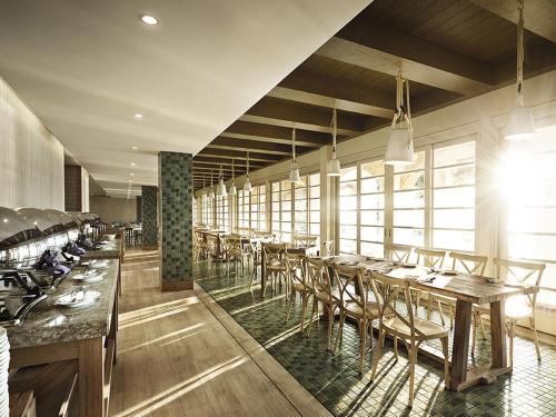 珍南海滩兰卡威世界度假村的有木桌椅和窗户的餐厅