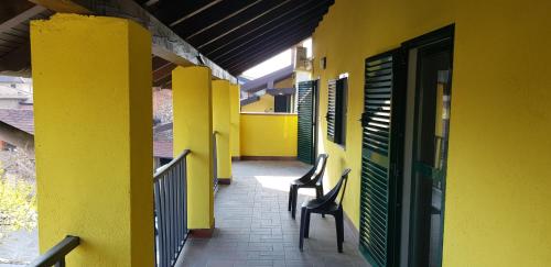 Agrate ConturbiaにあるIl terrazzo sul giardinoの椅子2脚と黄色い建物のある廊下
