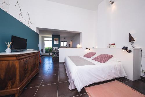 1 dormitorio con 1 cama blanca grande y TV de pantalla plana en Le Mas de Plein Pagnier, en Mazan