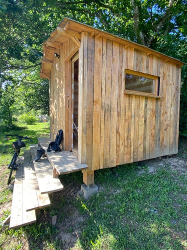a wooden cabin with a bench in a yard at CabaNomade in Hôpital-Camfrout