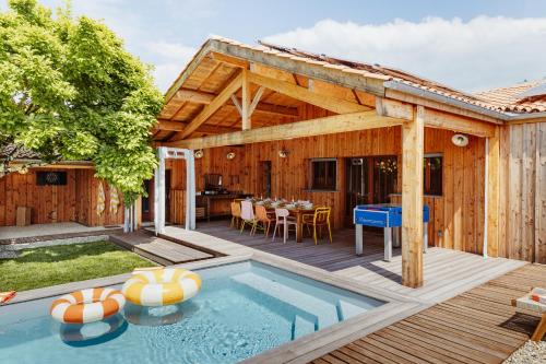 una casa de madera con piscina y terraza en La Cabane du Naissain 5 stars, en Saint-Georges-dʼOléron