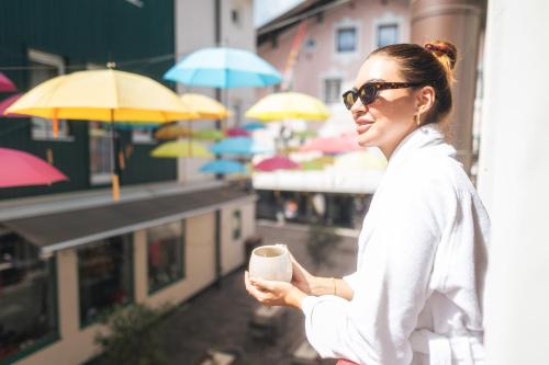 a woman in sunglasses holding a cup of coffee at Cella Central Historic Boutique Hotel in Zell am See