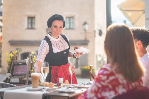 a woman standing at a table holding a piece of food at Cella Central Historic Boutique Hotel in Zell am See