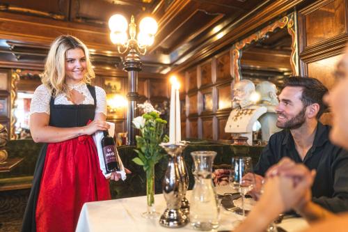 a woman standing in a restaurant holding a bottle of wine at Cella Central Historic Boutique Hotel in Zell am See