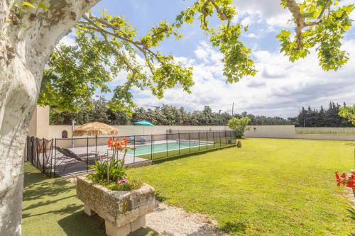 un jardin avec une piscine et une clôture dans l'établissement Le Petit Mas Rey, à Eyragues