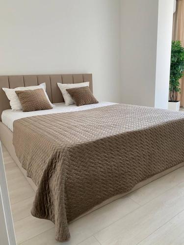 a bed with a brown blanket and pillows on it at ATLANT luxury Big Family Five Apart - ТЦ ДЕПОТ in Chernivtsi