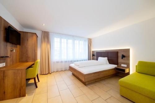 a bedroom with a bed and a desk and a couch at Hotel Schützenhaus in Uznach