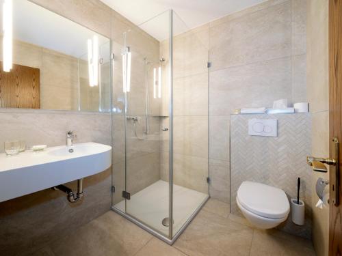 a bathroom with a shower and a toilet and a sink at Hotel Schützenhaus in Uznach