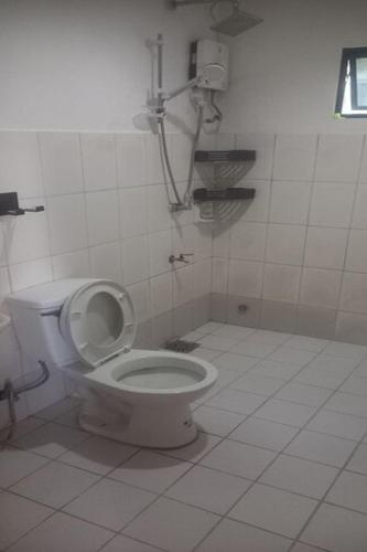 a bathroom with a toilet in a white tiled room at Dolphin Bay Resort Puerto Galera in San Isidro