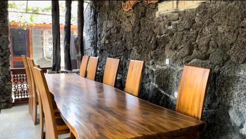 a wooden table with chairs and a stone wall at Nuwono Tasya Syariah in Bandar Lampung