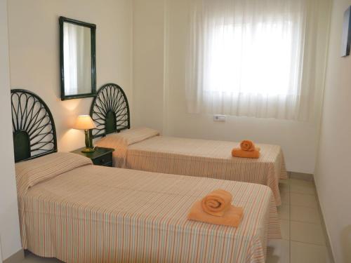 Una habitación con tres camas con toallas naranjas encima. en Estartit Park 3-2, en Torroella de Montgrí